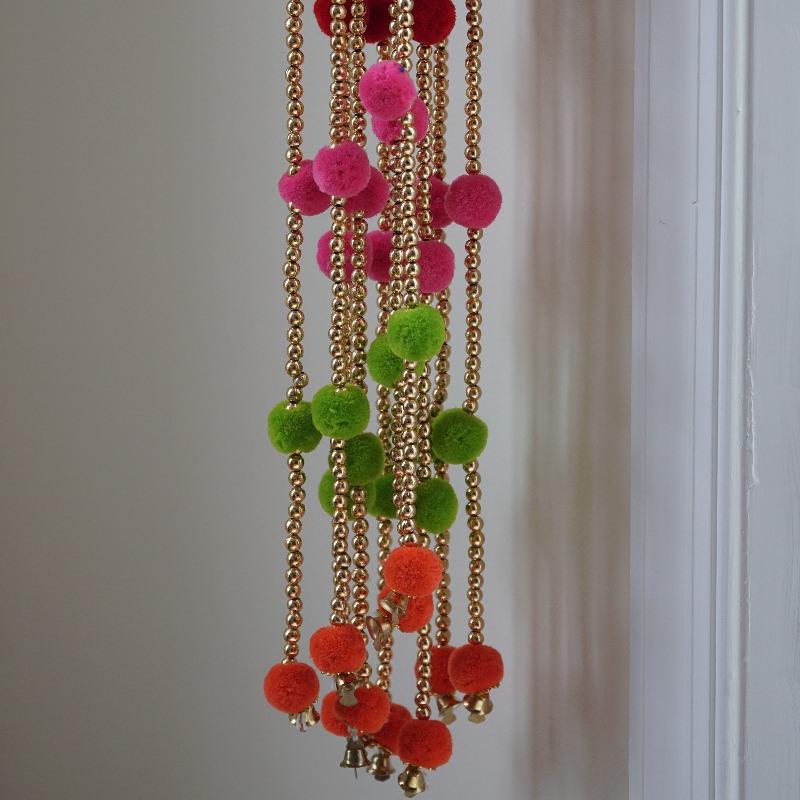 boho pompom photobooth backdrop with tiny bells and golden beads.