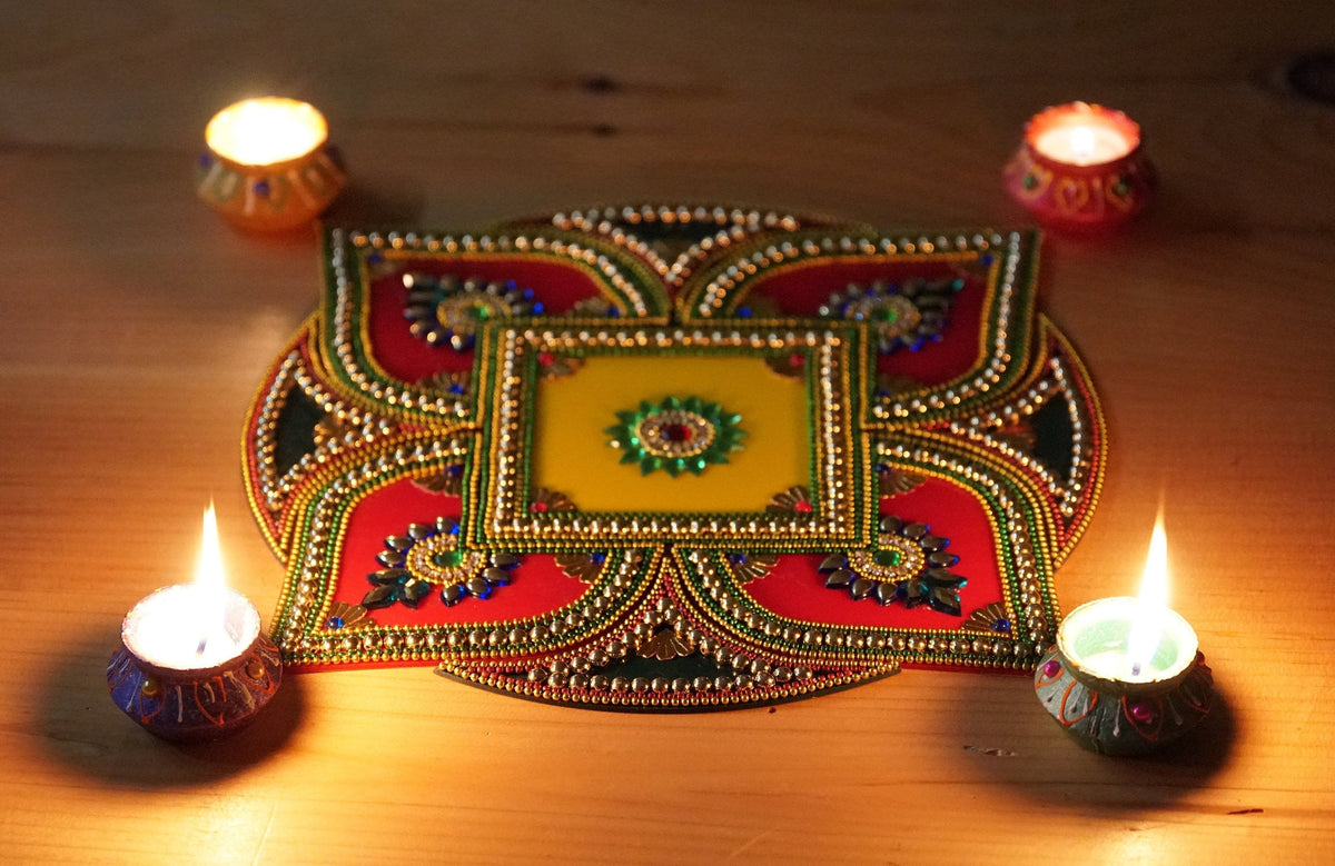 Square red yellow and green floral rangoli arrangement with four wax diyas