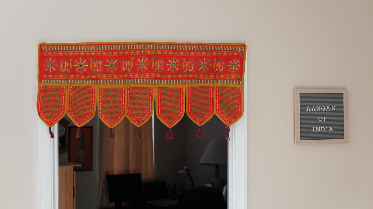 Red embroidered toran displayed above a doorway