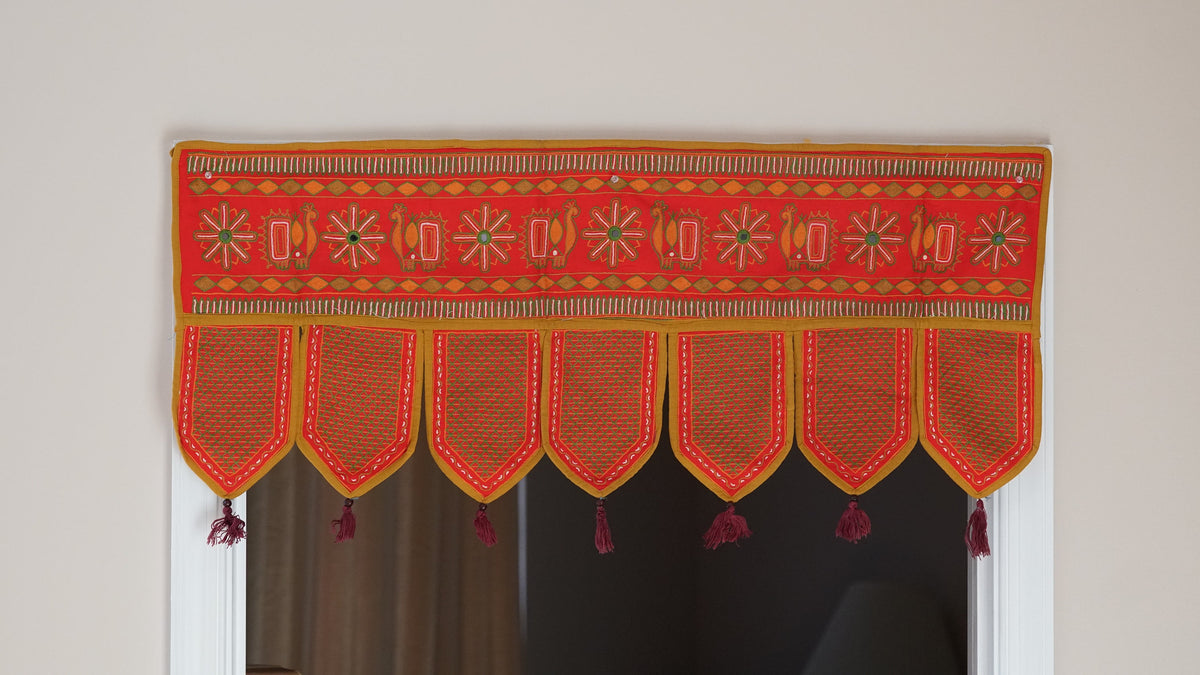 Red embroidered door toran with seven leaf-shaped panels and small tassels