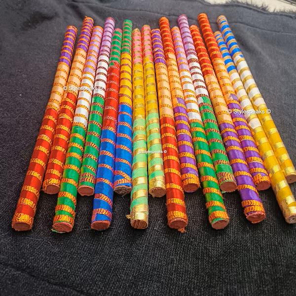 Assorted colorful ribbon-wrapped wooden dandiya sticks, Design 1; the pack includes 4 sticks